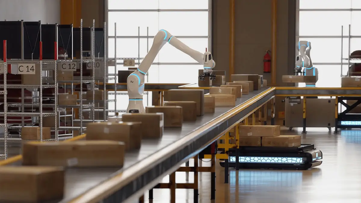 White robotic arms sorting boxes on a conveyor in an Amazon-style warehouse, official AWS Physical AI Toolchain announcement image