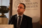 Economist Daron Acemoglu speaking at a Royal Swedish Academy of Sciences press conference behind a name plate