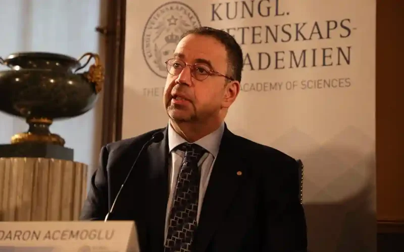 Economist Daron Acemoglu speaking at a Royal Swedish Academy of Sciences press conference behind a name plate